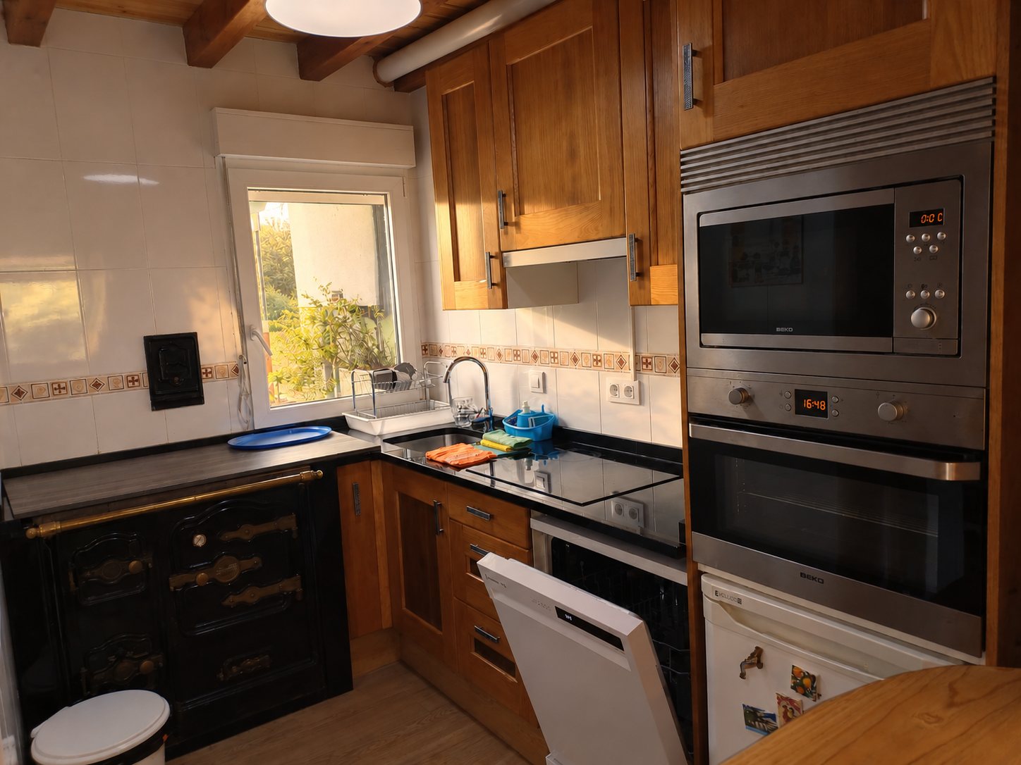 Cocina equipada con horno, microondas, lavavajillas y cocina de leña