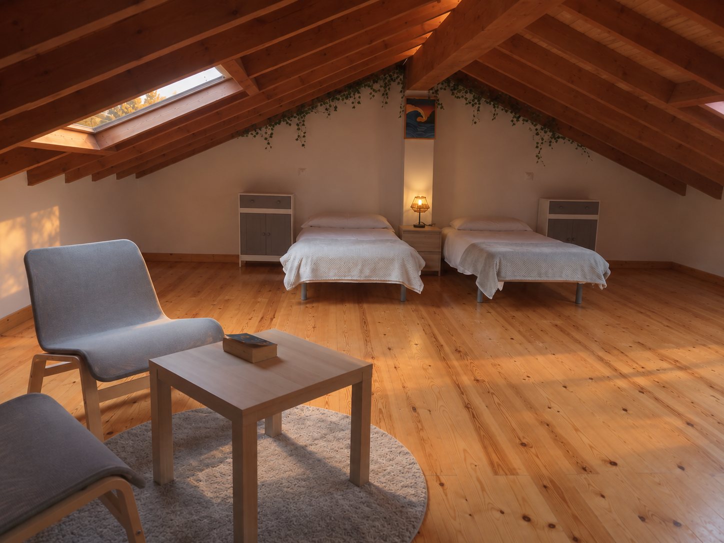 Dormitorio abuhardillado con vigas de madera, claraboya y zona de estar